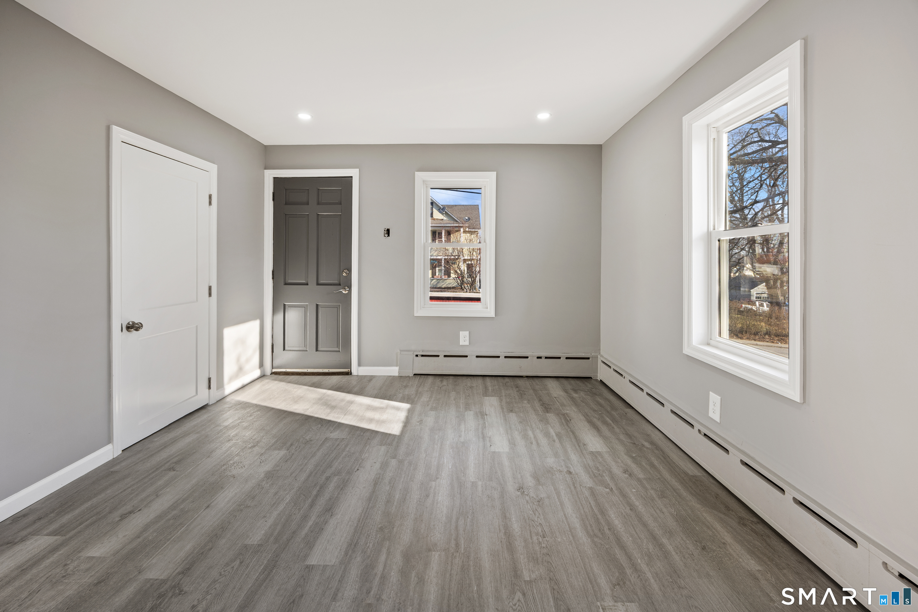153 Funston Avenue, Unit 1 Torrington, CT 06790 - Photo 5 of 16 an empty room with wooden floor and windows