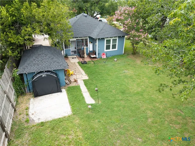 a view of a house with a big yard and large trees
