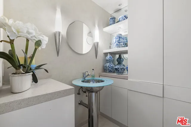 a bathroom with a sink a mirror and a potted plant