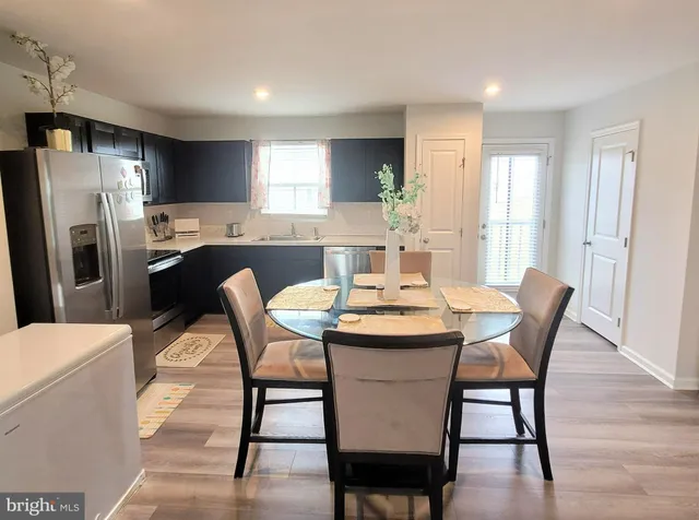 a kitchen with stainless steel appliances granite countertop a stove top oven a sink dishwasher a dining table and chairs with wooden floor