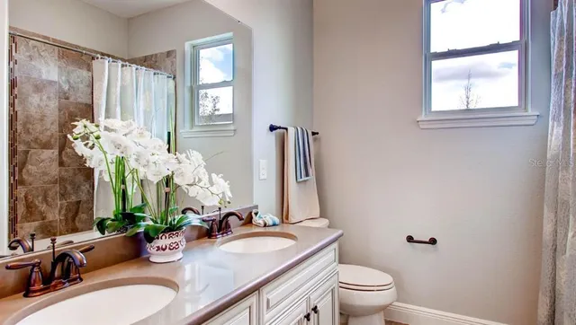 a bathroom with a granite countertop sink a toilet and a mirror