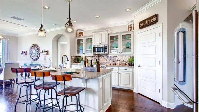 a very nice looking kitchen with granite countertop a table chairs and wooden floor