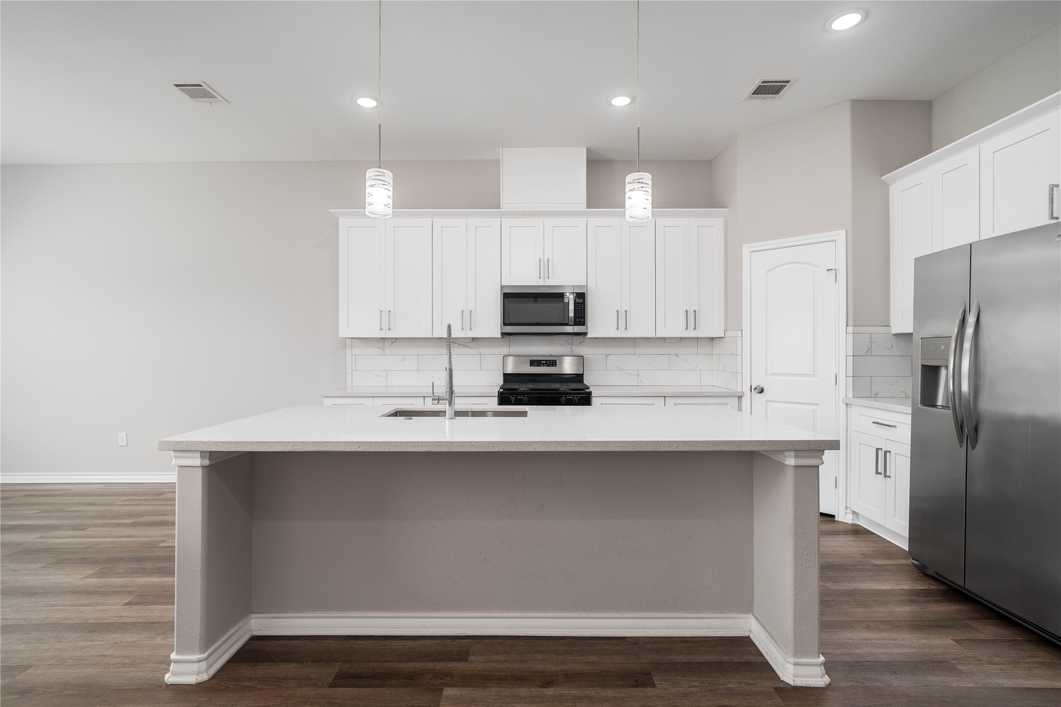 231 McCormick Street Columbus, TX 78934 - Photo 3 of 27 Kitchen – Stunning open-concept kitchen featuring a large center island with seating, quartz countertops, and stylish pendant lighting.