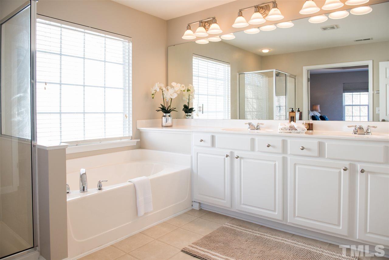 7725 Jackson Dane Drive Raleigh, NC 27613 - Photo 14 of 24 a bathroom with a sink a large mirror and a bathtub with shower
