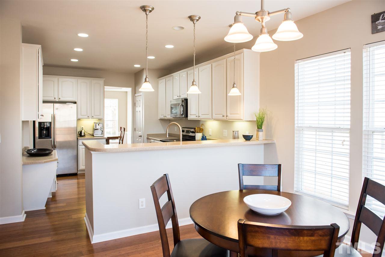 7725 Jackson Dane Drive Raleigh, NC 27613 - Photo 6 of 24 a kitchen with stainless steel appliances kitchen island granite countertop a table chairs and a refrigerator
