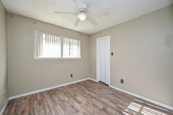 a view of empty room with wooden floor and fan