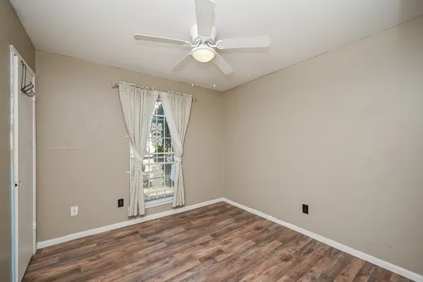 an empty room with windows and ceiling fan