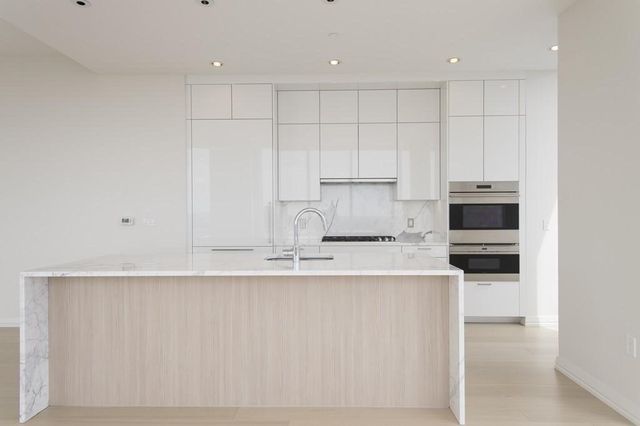 a kitchen with kitchen island white cabinets and stainless steel appliances
