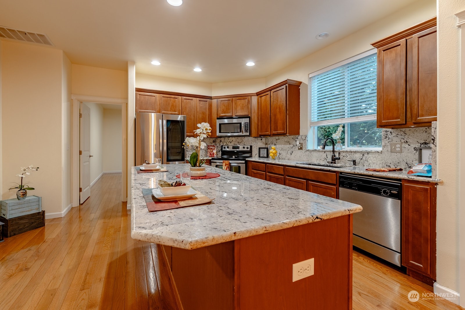 1324 Farina Loop Southeast Olympia, WA 98513 - Photo 9 of 40 a kitchen with kitchen island granite countertop wooden cabinets a sink dishwasher and a stove with wooden floor