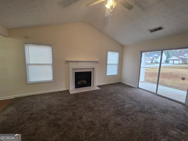 an empty room with windows and fireplace
