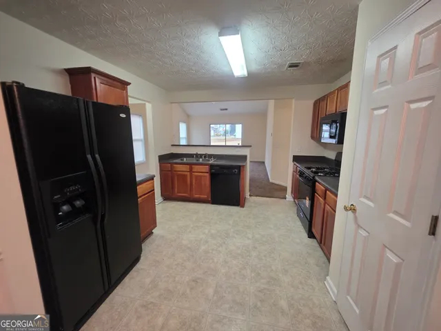 a large kitchen with stainless steel appliances granite countertop a refrigerator and a stove