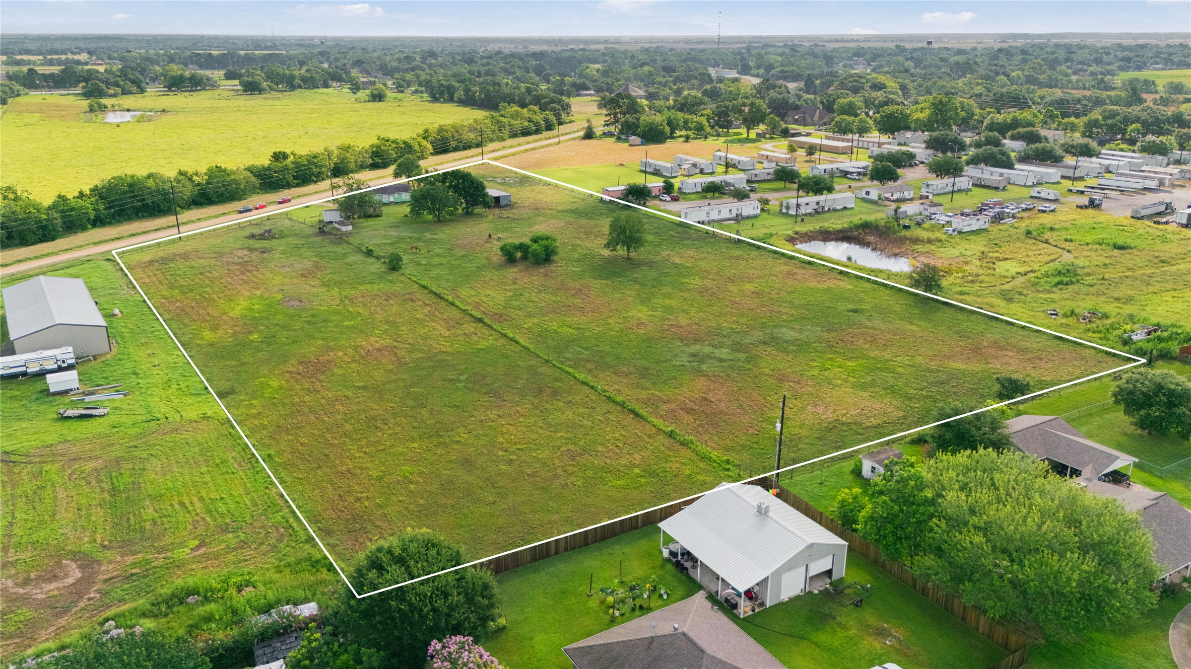 765 Norcross Road Wallis, TX 77485 - Photo 42 of 42 his aerial photo showcases an outline of the spacious, large plot of land in a rural setting, featuring a few small structures and bordering a residential area. The surrounding landscape is lush offering a peaceful countryside view with ample open space.