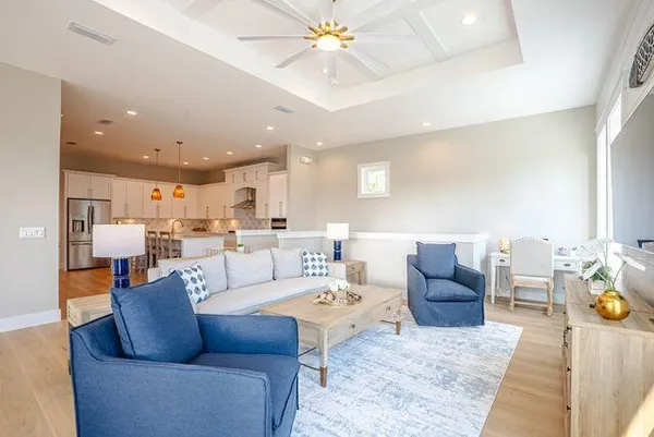 a living room with furniture kitchen view and a chandelier