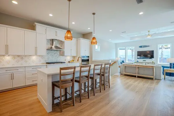 a kitchen with stainless steel appliances kitchen island granite countertop a wooden floor and white cabinets