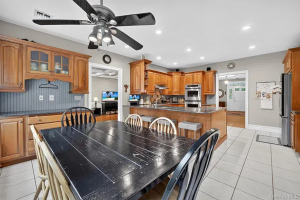 a large kitchen with stainless steel appliances granite countertop a stove a sink a dining table and chairs with wooden floor