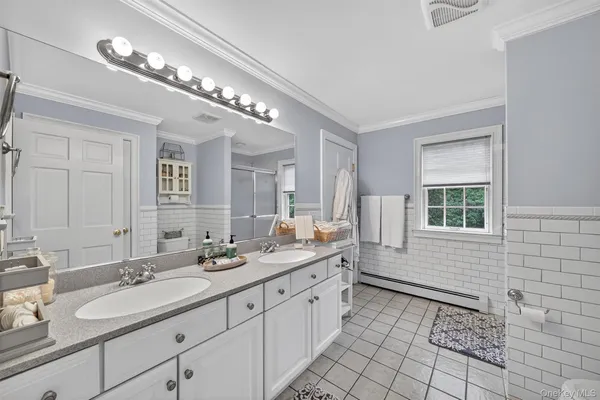 a spacious bathroom with a double vanity sink a large mirror and a shower
