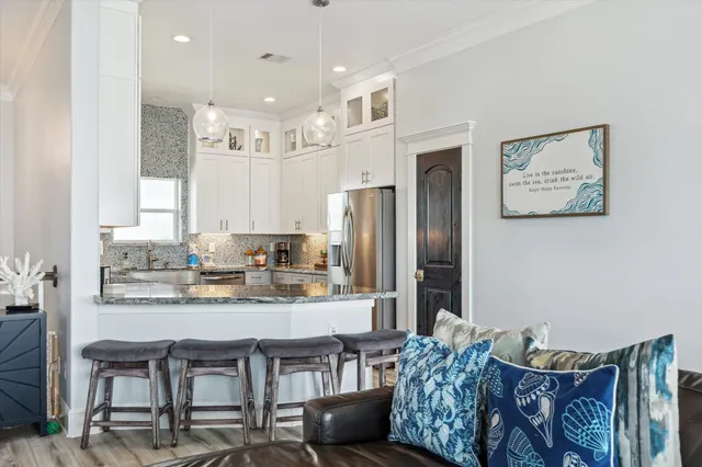 a kitchen with stainless steel appliances granite countertop a table chairs sink and cabinets