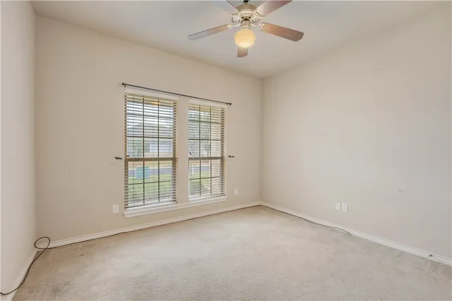 an empty room with windows and chandelier fan