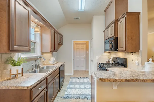a kitchen with granite countertop a sink a counter top space and cabinets