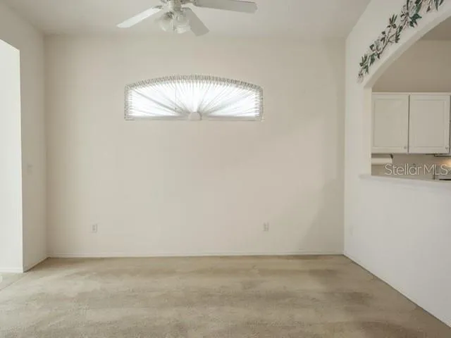 an empty room with a chandelier fan and wooden floor