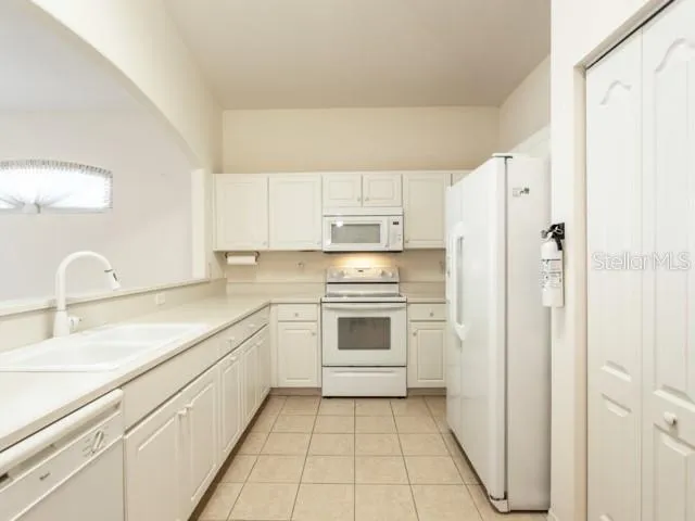a kitchen with white cabinets and white appliances