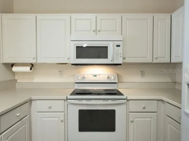 a kitchen with granite countertop white cabinets and stainless steel appliances