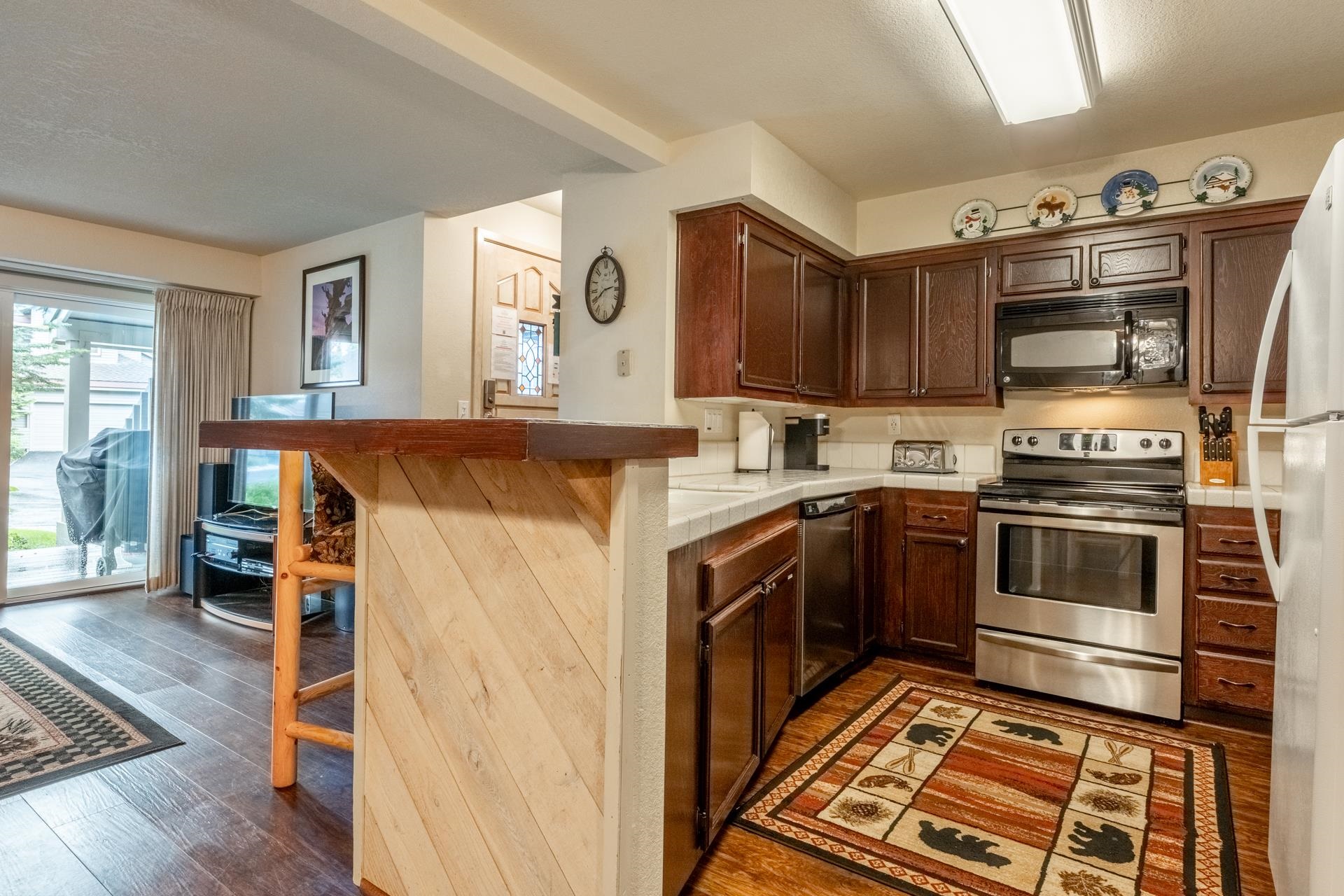 613 Golden Creek Road, Unit 613 Mammoth Lakes, CA 93546 - Photo 4 of 24 Kitchen with a kitchen bar, stainless steel appliances, tile countertops, dark wood-style flooring, and a peninsula