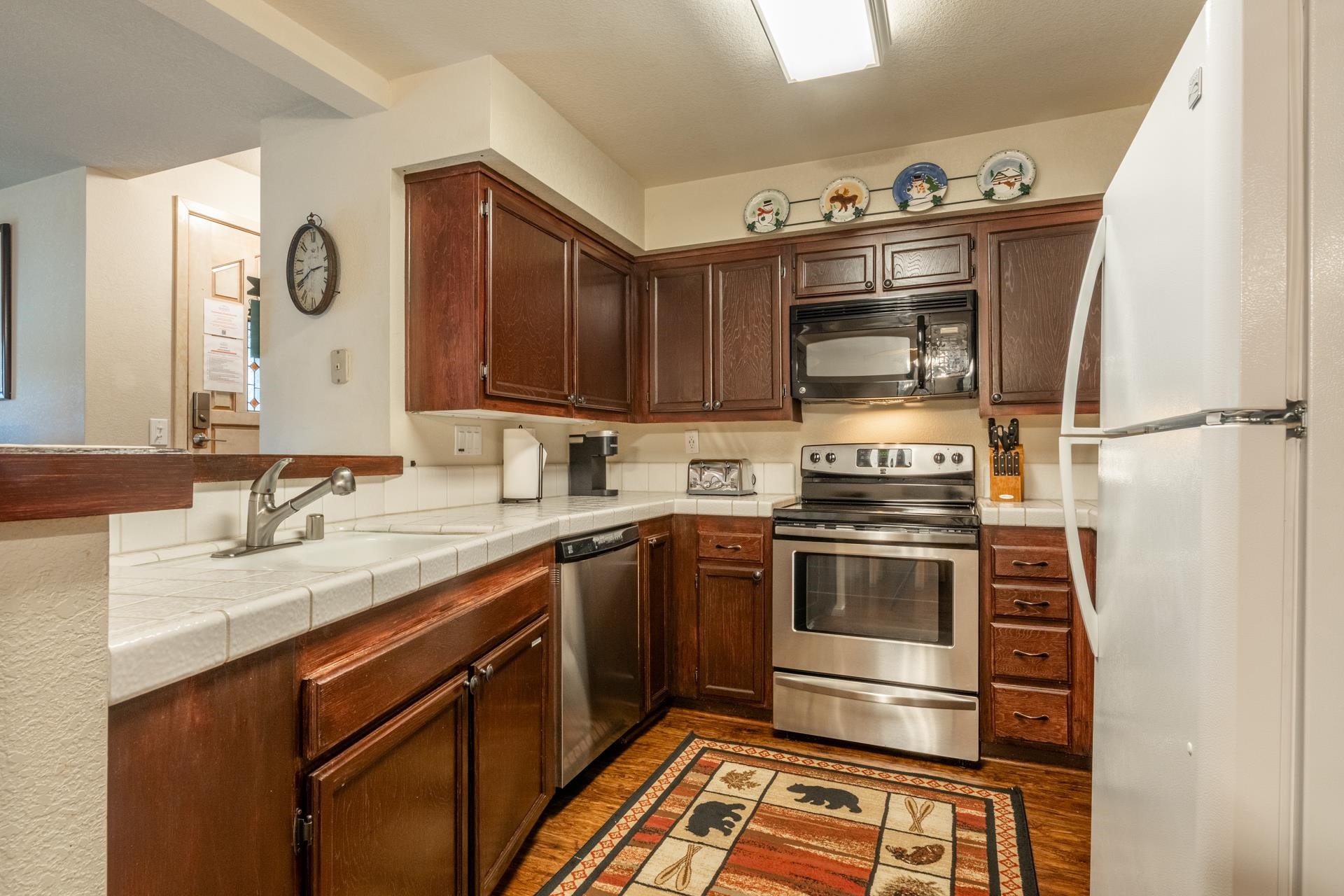 613 Golden Creek Road, Unit 613 Mammoth Lakes, CA 93546 - Photo 9 of 24 Kitchen with stainless steel appliances, tile counters, dark wood-style floors, and dark brown cabinets