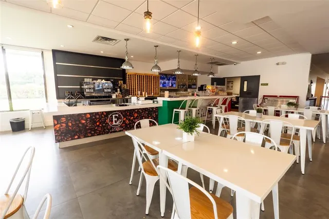 a kitchen with stainless steel appliances kitchen island granite countertop a dining table chairs and a refrigerator