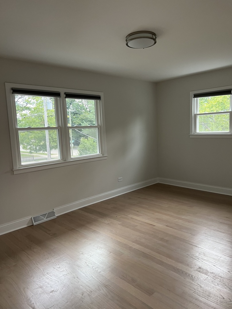 1106 Waukegan Road Deerfield, IL 60015 - Photo 17 of 29 a view of an empty room with wooden floor and a window