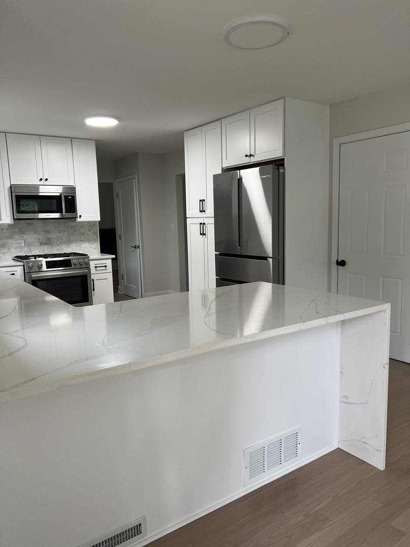 1106 Waukegan Road Deerfield, IL 60015 - Photo 8 of 29 a kitchen with stainless steel appliances a refrigerator and a stove top oven