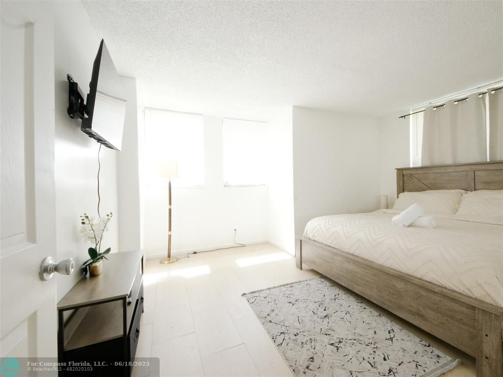 1920 North Congress Avenue, Unit 105 West Palm Beach, FL 33401 - Photo 15 of 19 a bedroom with a bed and flat screen tv
