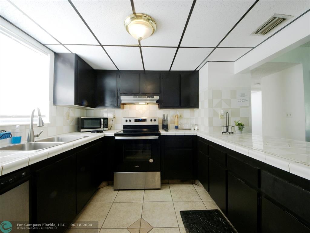 1920 North Congress Avenue, Unit 105 West Palm Beach, FL 33401 - Photo 4 of 19 a kitchen with a sink stainless steel appliances and cabinets
