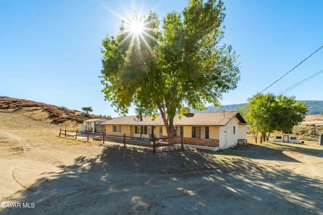a view of a white house next to a road and yard