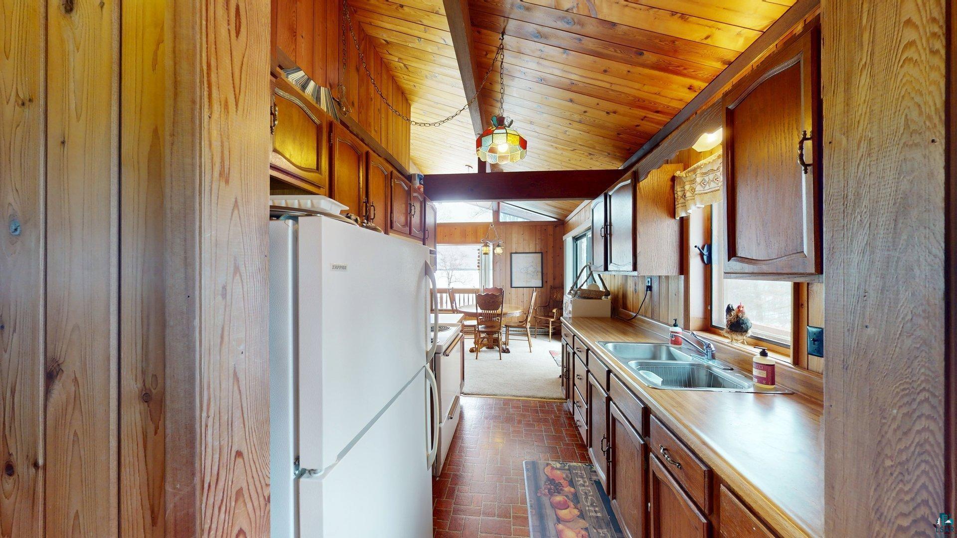 4512 Krollman Road Orr, MN 55771 - Photo 22 of 38 Kitchen featuring wooden ceiling, a sink, light countertops, white appliances, and brick floor