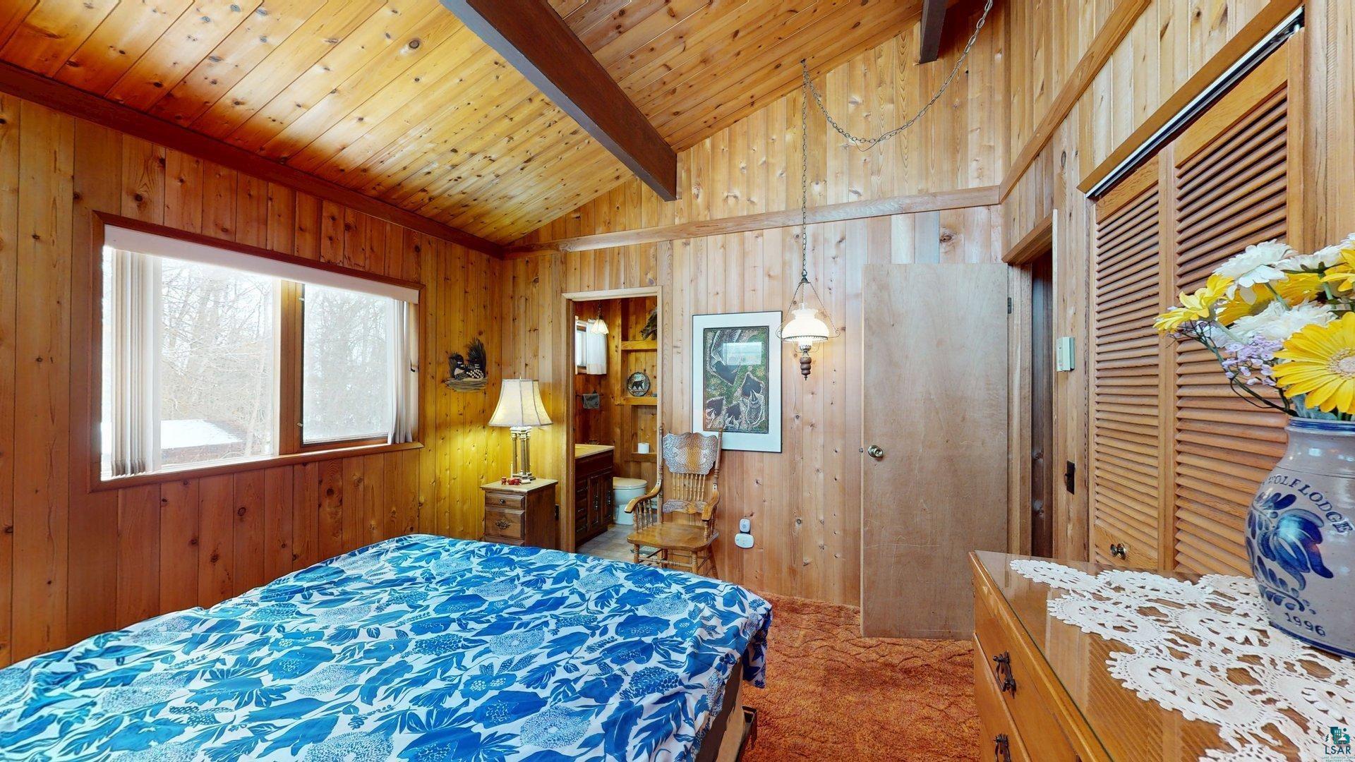 4512 Krollman Road Orr, MN 55771 - Photo 26 of 38 Bedroom featuring wooden walls, carpet, and lofted ceiling with beams