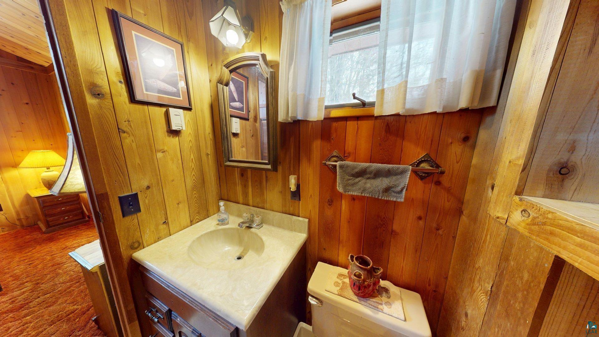 4512 Krollman Road Orr, MN 55771 - Photo 27 of 38 Half bathroom with toilet, wood walls, and vanity