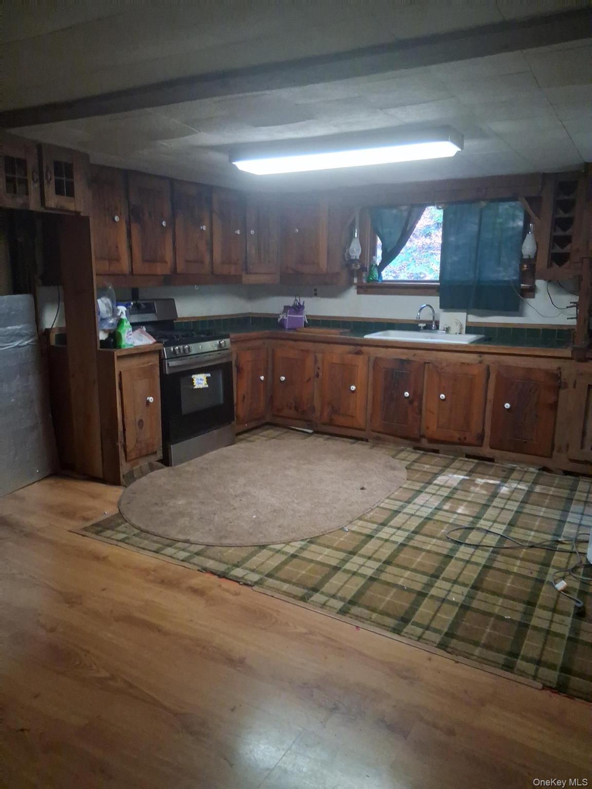 84 N Road Red Hook, NY 12571 - Photo 6 of 22 Kitchen with stainless steel gas range oven, brown cabinets, light wood-style flooring, and refrigerator