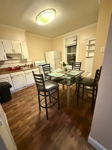 a kitchen with stainless steel appliances granite countertop a stove top oven a dining table and chairs with wooden floor