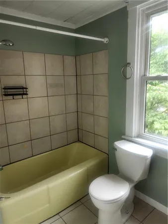 a white toilet and tub sitting next to a window