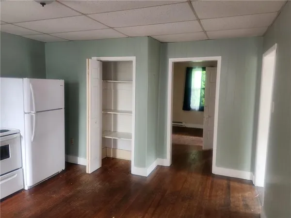 a view of a hallway with wooden floor and a refrigerator