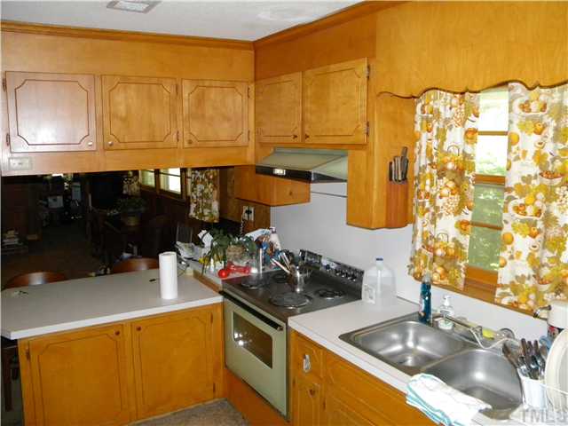 1426 Trinity Circle Raleigh, NC 27607 - Photo 3 of 12 The car port door enters directly into the kitchen. The kitchen overlooks the family room with a log fire place.