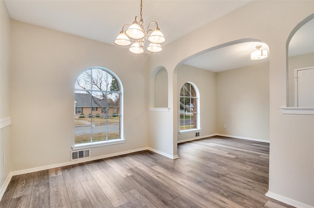 2244 Homeway Circle Dallas, TX 75228 - Photo 2 of 12 Empty room featuring arched walkways, light wood finished floors, and a chandelier