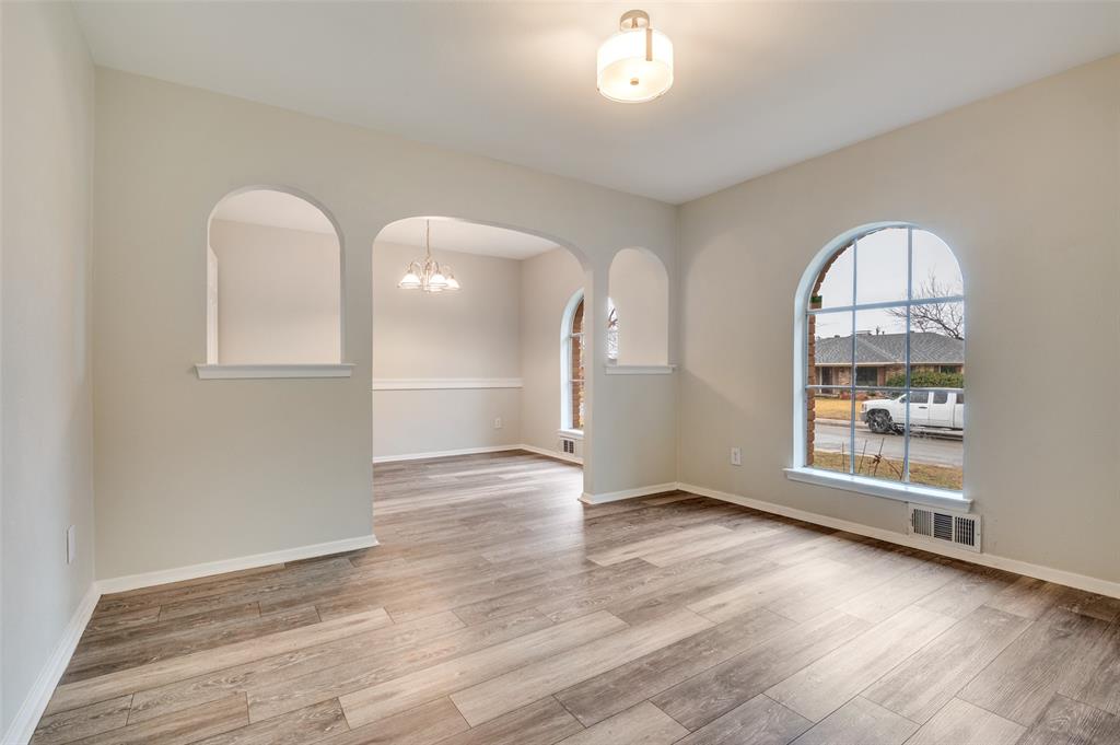 2244 Homeway Circle Dallas, TX 75228 - Photo 3 of 12 Empty room with a chandelier, arched walkways, and light wood-style floors