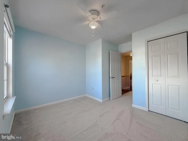 an empty room with closet and a ceiling fan