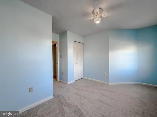 an empty room with closet and a ceiling fan