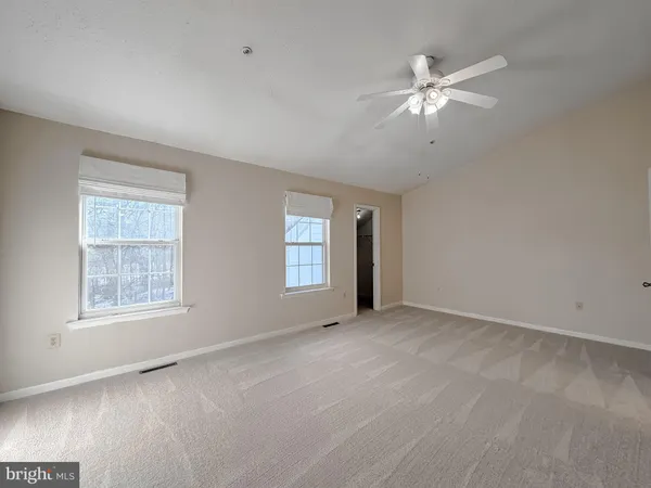 a view of an empty room with chandelier fan and a window