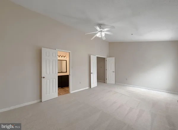 an empty room with chandelier fan and windows