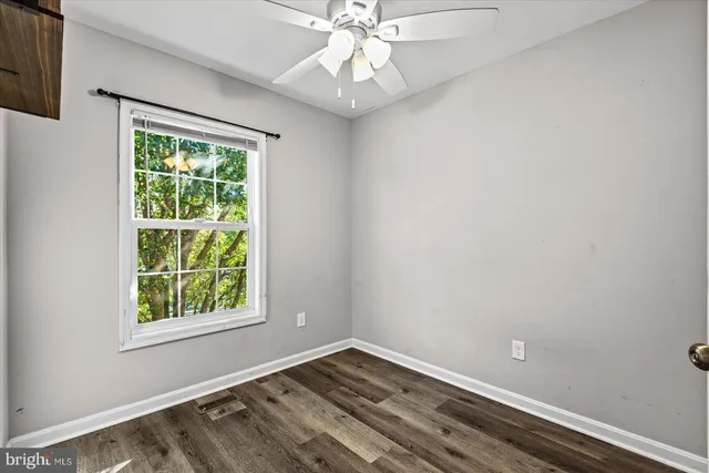 an empty room with a window and ceiling fan