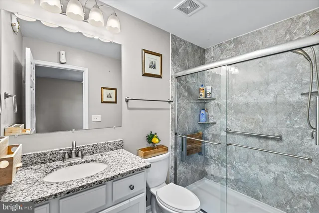 a bathroom with a granite countertop sink mirror vanity and toilet